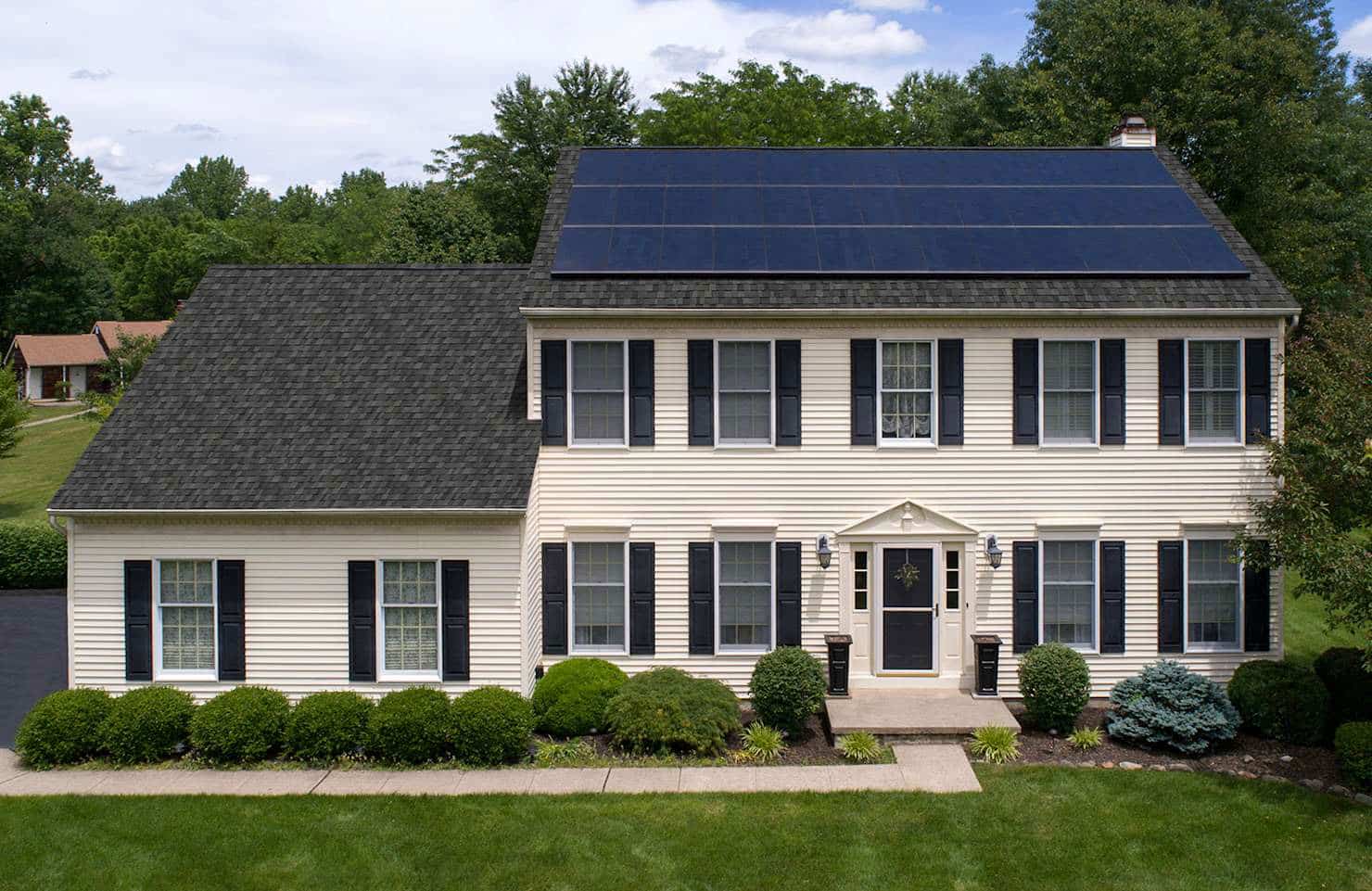 black solar panels on a dark roof of a white house